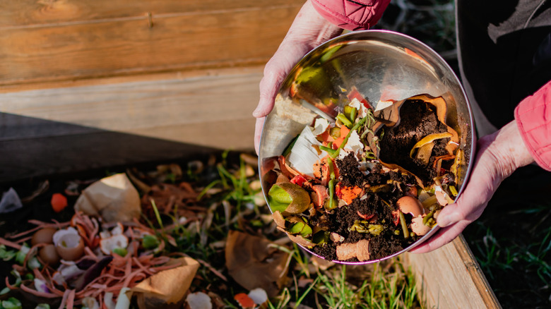 person adding compost with coffee grounds to the garden