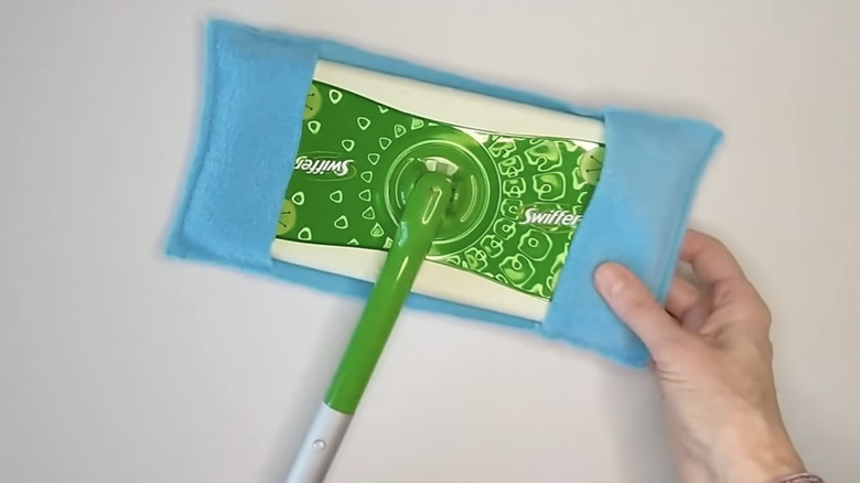 Woman's hand putting a homemade mop cover onto a dry mop head.