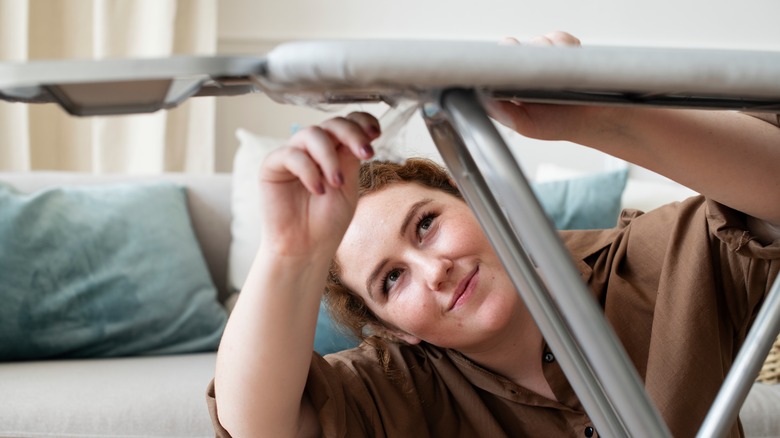 A woman setting up an ironing board