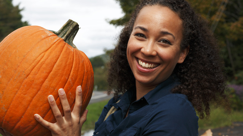 Smiling person holding pumpkin