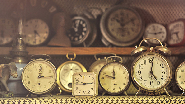 An assortment of vintage alarm clocks clustered inside a display cabinet.