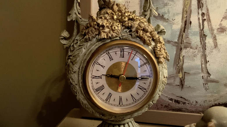 An old alarm clock is adorned with glue-on baroque embellishments sculpted from air dry clay and spray painted gold.