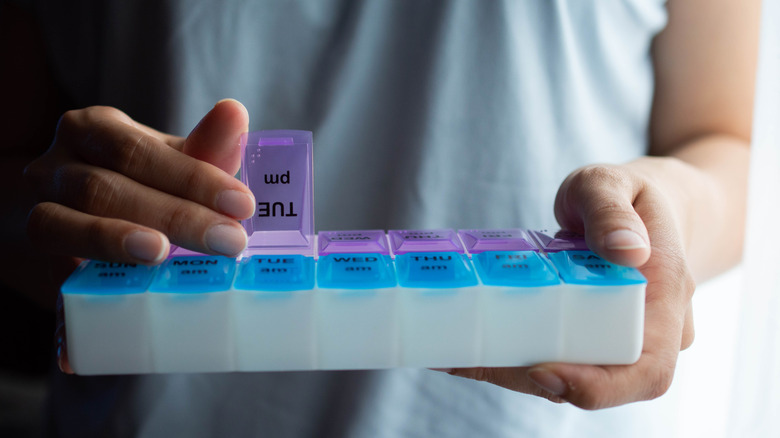 Person holding a blue and purple pill organizer