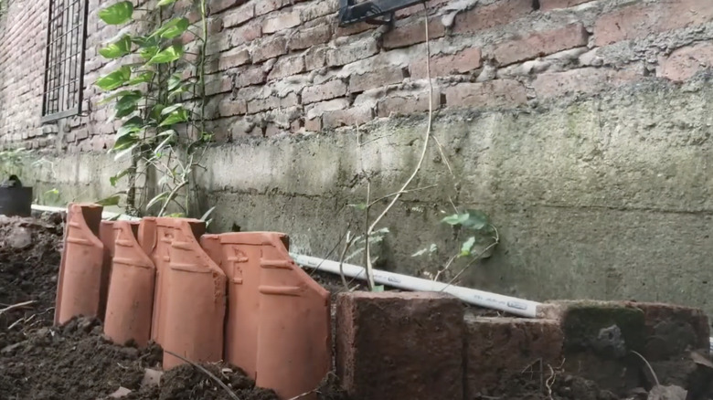 Broken terracotta flower pots are being used to create a new garden bed retaining wall.