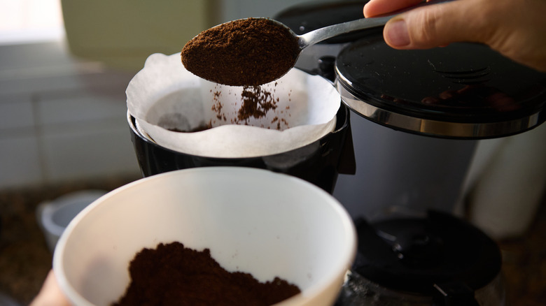 Fresh coffee grounds being placed in coffee filter