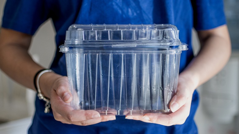 Person holding empty plastic food storage container