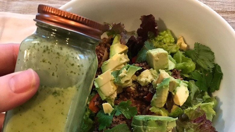 Salad dressing in glass spice jar over salad