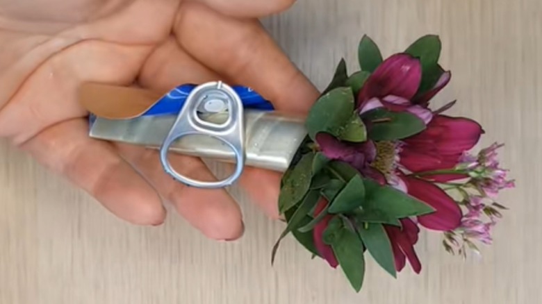 A DIY floral sleeve made from the lid of a tin can.