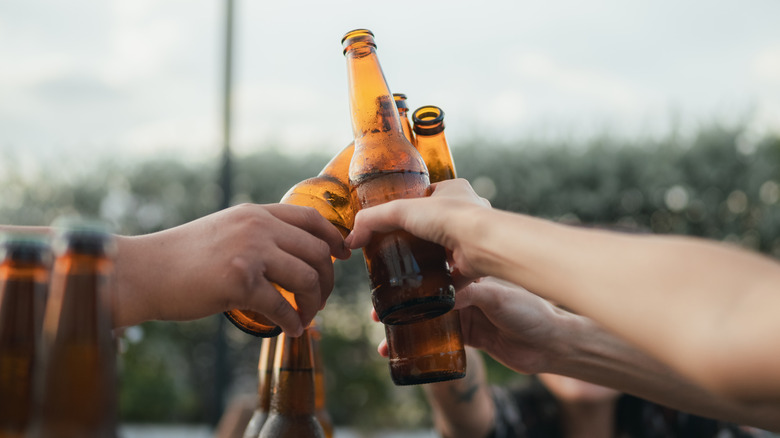 A group of people clinking their beer bottles together