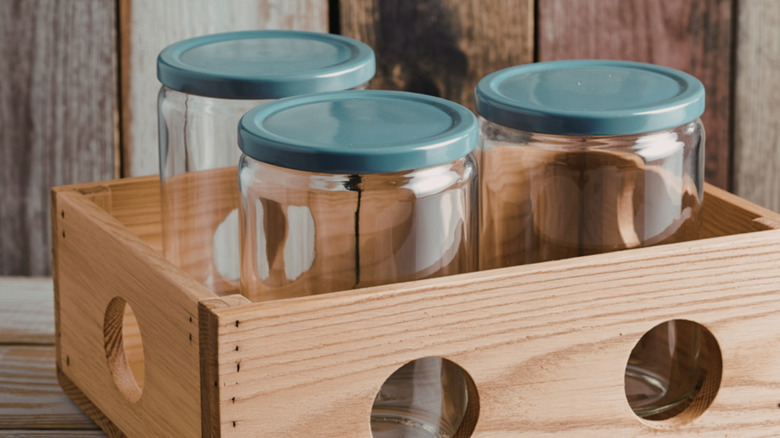 Glass jars with lids sitting in wooden crate