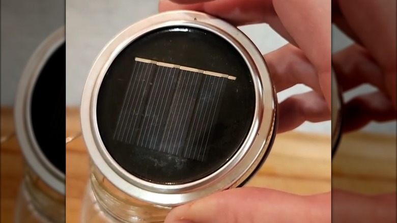 Someone holding a mason jar lid with solar light in it.