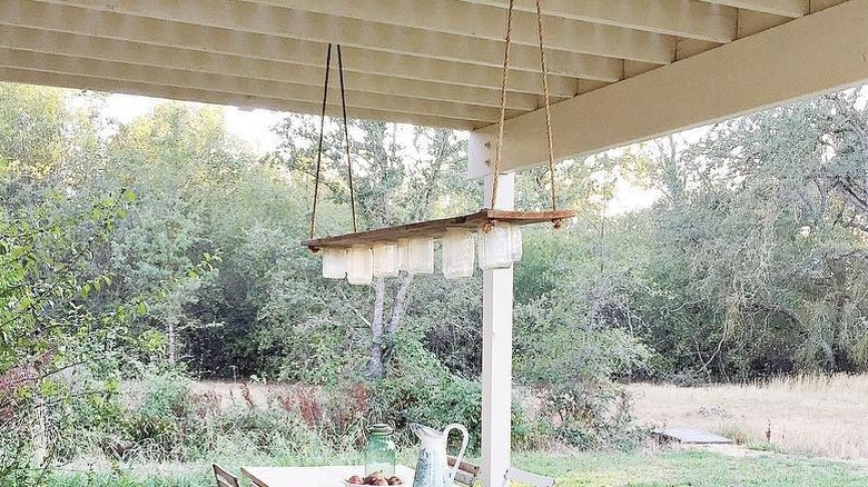 A table and mason jar chandelier hanging above.