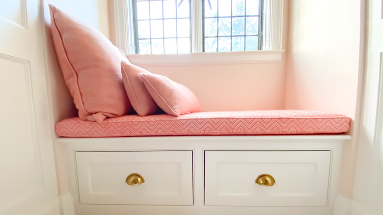 pink seat cushion and pillows on a window bench