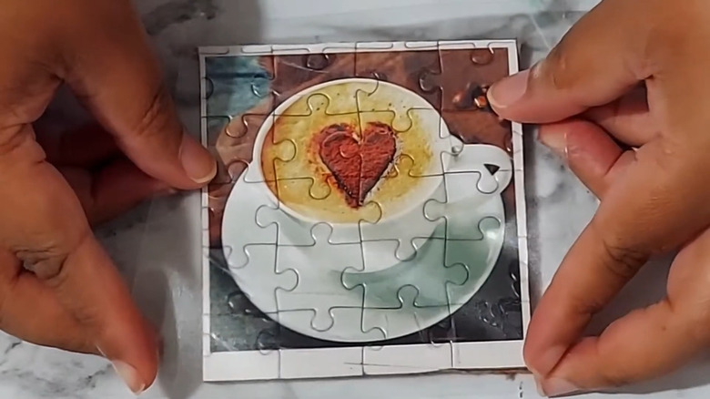 Hands sealing a homemade coaster out of puzzle pieces