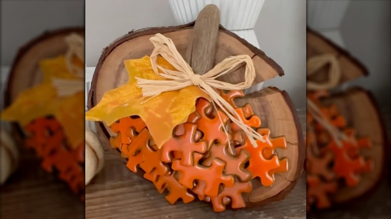 Wooden pumpkin cut-out decorated with orange pieces and an artificial leaf