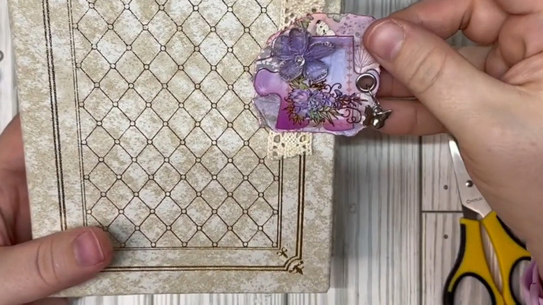 Woman's hand holding a purple floral decorated puzzle piece with a small butterfly charm attached