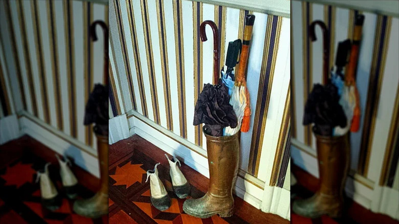 Black rain boot in entryway stuffed with umbrellas