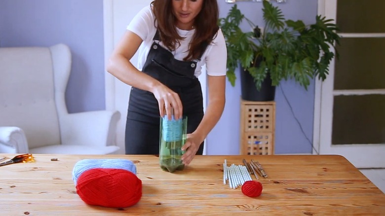 Woman adding a bunch of bamboo tubes inside a plastic bottle
