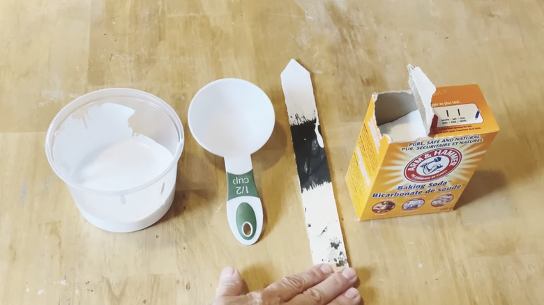 Ingredients to make textured paint using baking soda laid out on a wooden tabletop.