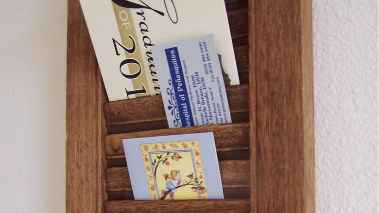 Cards and images slotted into a repurposed window shutter for wall decor.