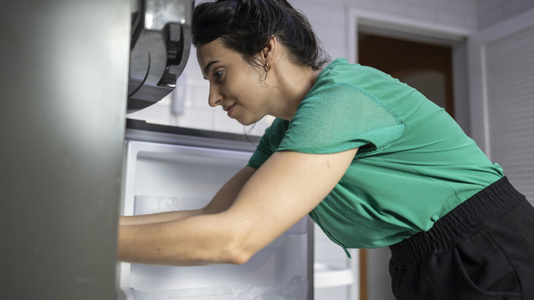 woman reaching into fridge