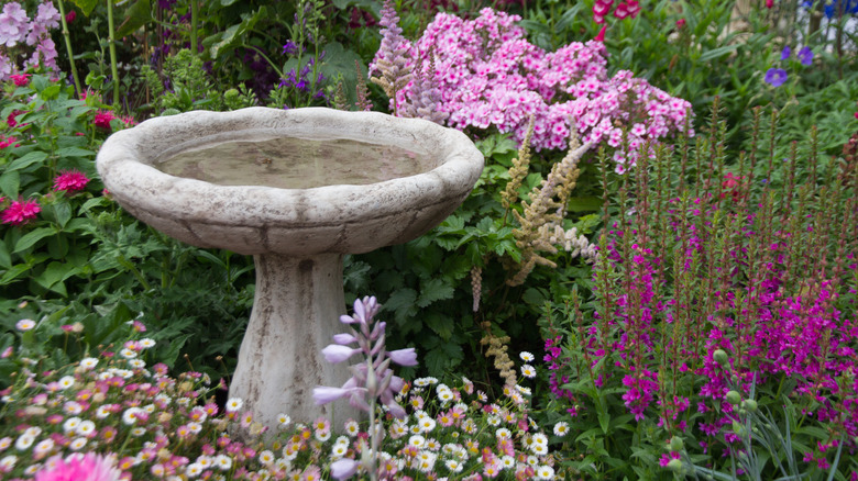 A bird bath in a flower garden