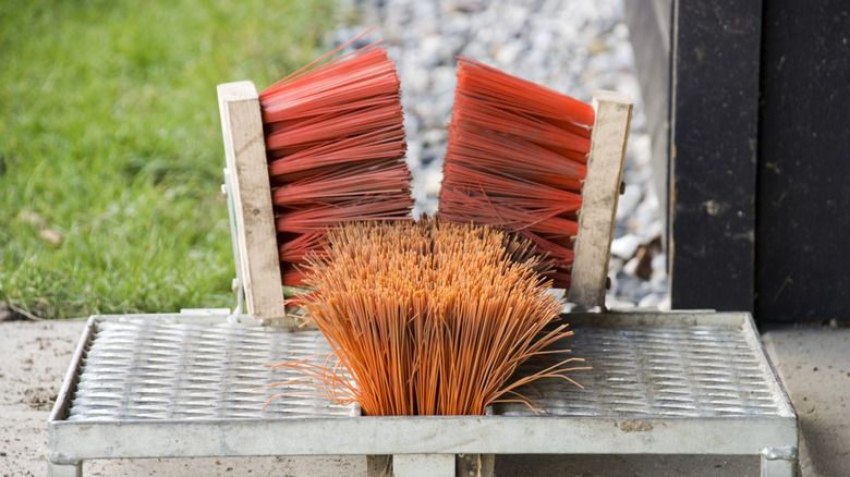 Red and orange boot scraper on metal base.