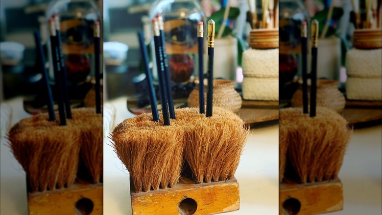 Vintage push broom holding pencils.
