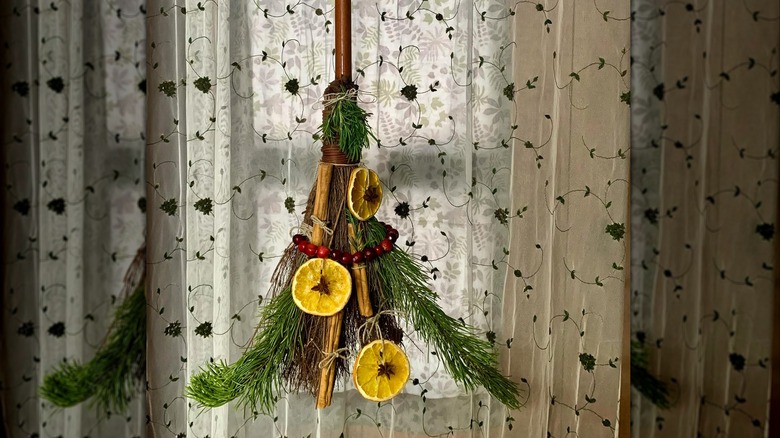 Cinnamon broom hanging in front of a curtain.