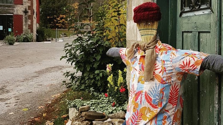 Broom scarecrow outside of green door.