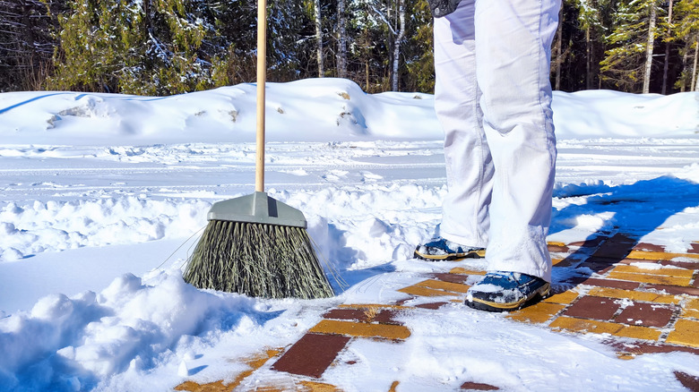 Someone sweeping snow off a sidewalk.