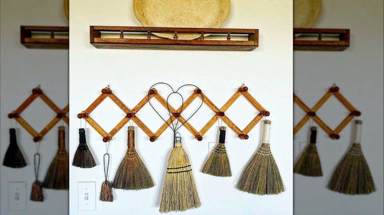 Six brooms hanging on a wooden rack.