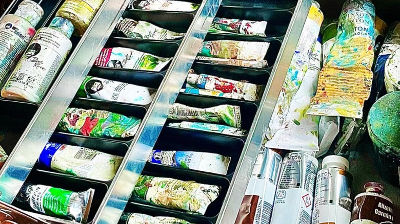 A metal tackle box holding paints and supplies.