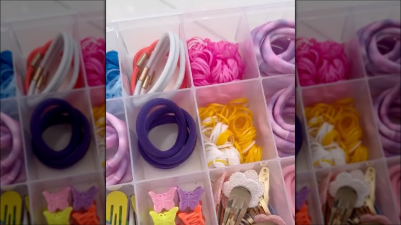 A clear tackle box holding hair ties.