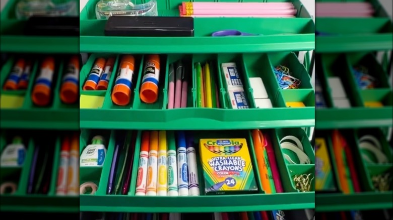 Green tackle box filled with school supplies.