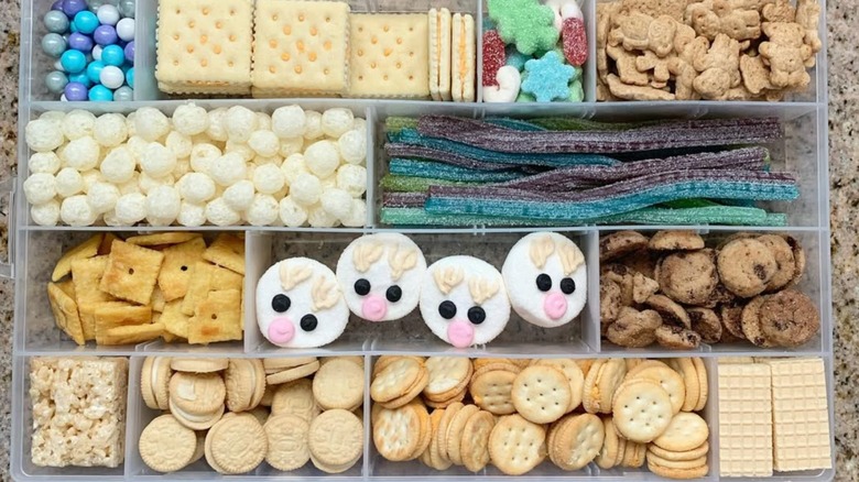 A clear tackle box filled with candy and snacks.