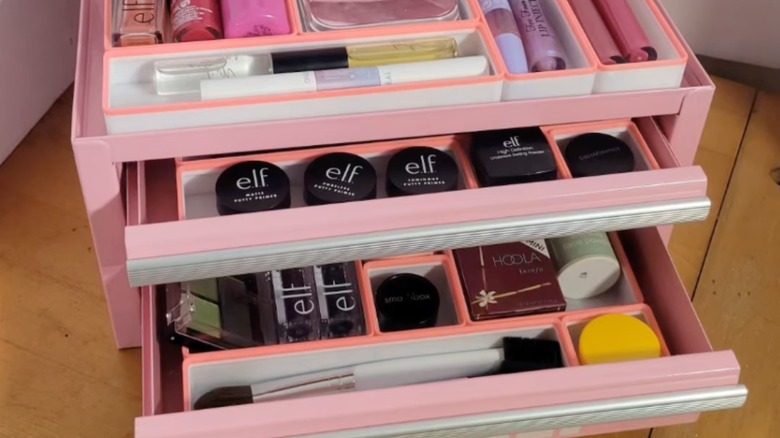 A pink tackle box holding makeup and tools.