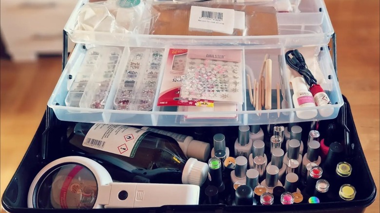 An open tackle box holding nail art and polish items.