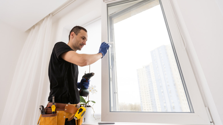 Man with a tool belt around his waist installing new windows