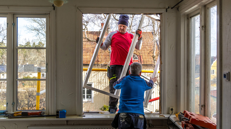 Two male professionals removing an old window frame