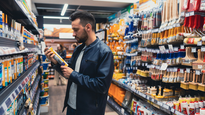 Man in a hardware store looking at sealants