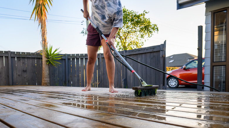 Man scrubs wooden deck