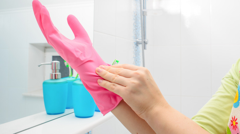 Person putting on pink gloves in bathroom