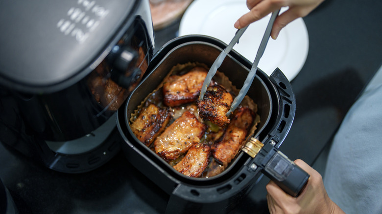 Person cooking meat in air fryer