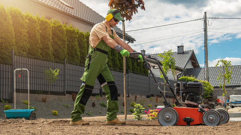 Man pushing lawn aerator in backyard