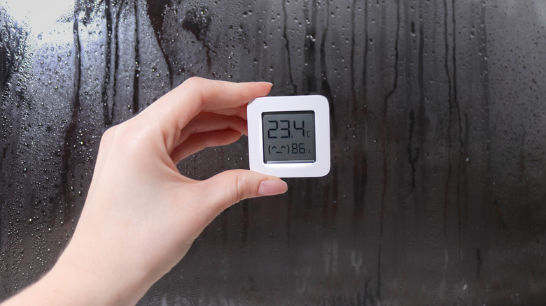 Hand holding a hygrometer near shower door