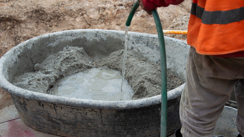 A garden hose adding water to concrete mix.