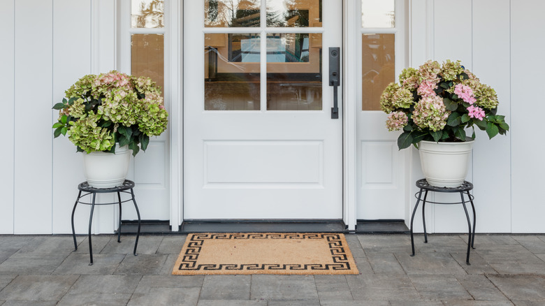 Front porch with door mat and vases of flowers