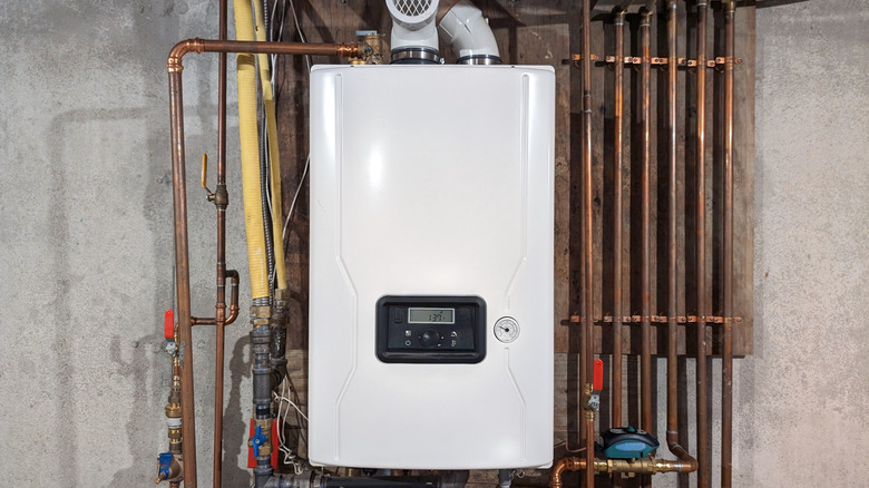 Compact tankless water heater surrounded by pipes in home