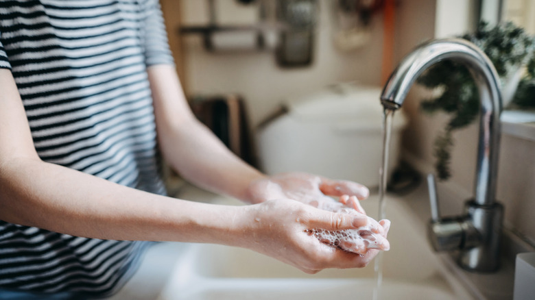 Person washing their hands at the sink with soap